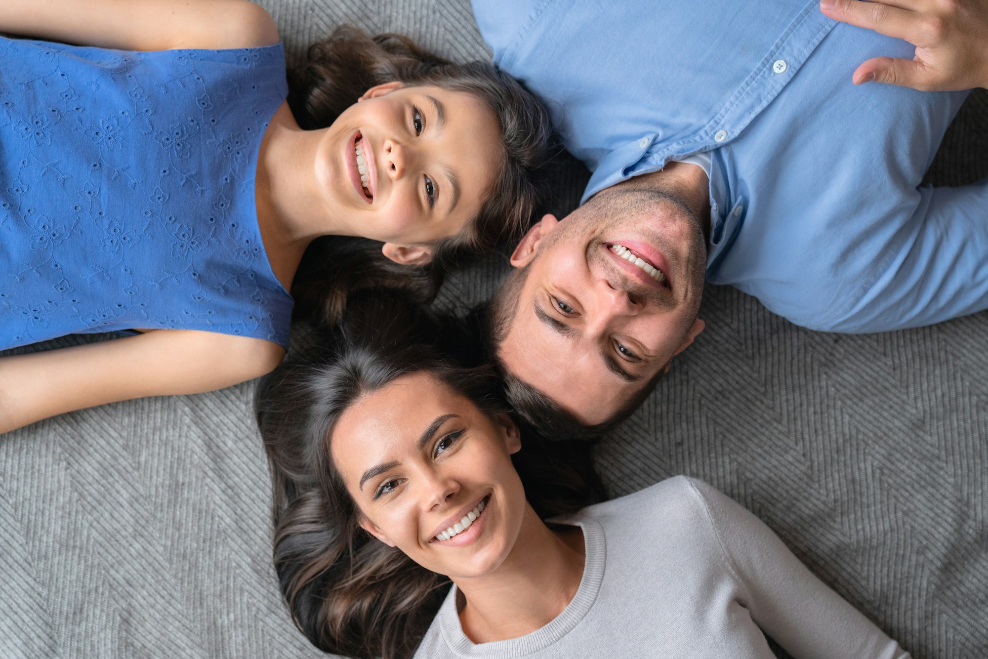 Happy family concept. Top view of happy family of three bonding to each other and smiling