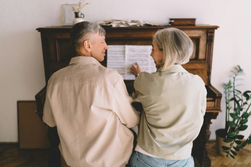 Happy senior couple playing piano together at home