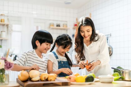 Portrait of parent and children stand at cooking counter preparing ingredient for dinner meal